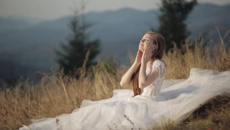 Beautiful-and-lovely-bride-in-wedding-dress-sitting-on-grass-on-mountain-slope