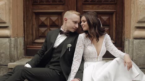 Newlyweds-love,-caucasian-groom-with-bride-sitting,-embracing,-hugs-in-city-street,-wedding-couple