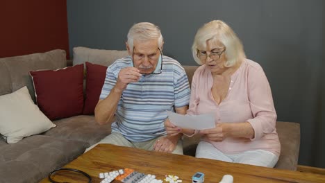 Senior-couple-looking-at-medicine-prescription,-pills,-tablets-at-home,-coronavirus-lockdown