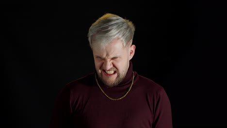 Disappointed-handsome-man-with-blue-eyes-showing-negative-and-agressive-emotion-on-black-background