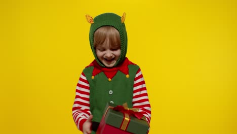 Kid-girl-in-Christmas-elf-Santa-helper-costume-getting,-receiving-present-gift-box.-New-Year-holiday