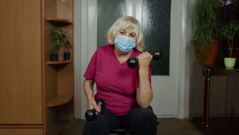 Senior-elderly-caucasian-woman-making-weightlifting-dumbbells-exercising-at-home-during-coronavirus