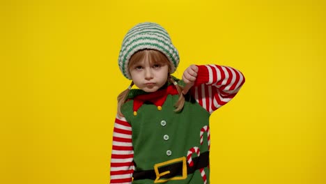 Displesed-kid-girl-in-Christmas-elf-Santa-helper-costume-keeps-thumb-down-and-shows-dislike-gesture