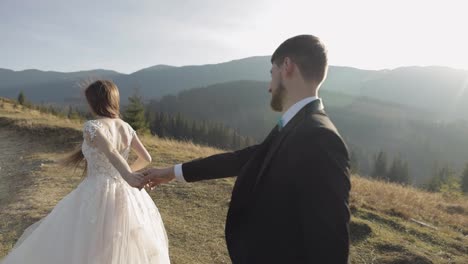 Newlyweds.-Caucasian-groom-with-bride-walking-on-mountain-slope.-Wedding-couple