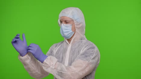 Medical-worker-doctor-in-personal-PPE-protective-suit-preparing,-wearing-hand-gloves-on-chroma-key