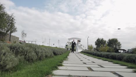 Newlyweds,-lovely-caucasian-bride-and-groom-running-along-path-during-wedding-ceremony-in-park