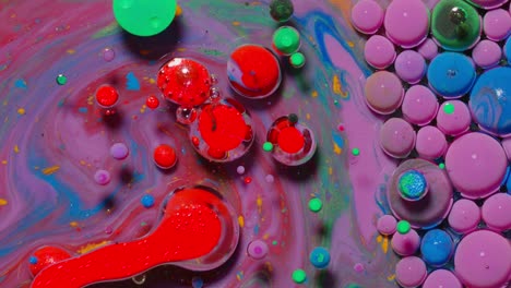 Ink-bubbles-mixed-with-liquid-substance-of-oil,-milk,-soap,-bright-acrylic-paint-on-colorful-surface