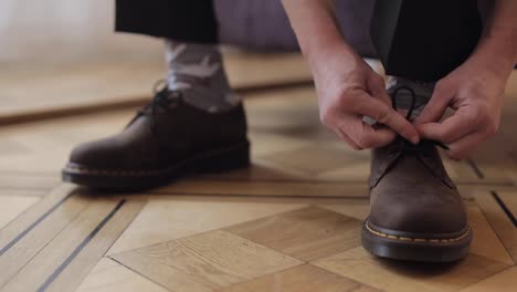 Close-up-hands-of-man-groom-adjusting,-wearing,-putting-his-wedding-shoes-in-hotel-room-near-window