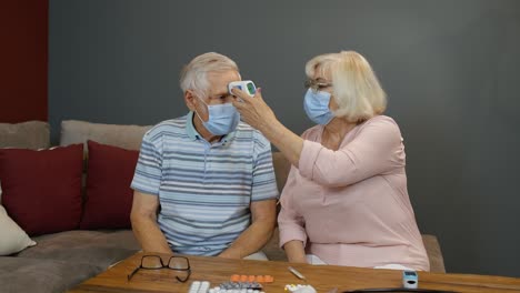 Senior-couple-measures-temperature-with-contactless-digital-thermometer-during-coronavirus-lockdown