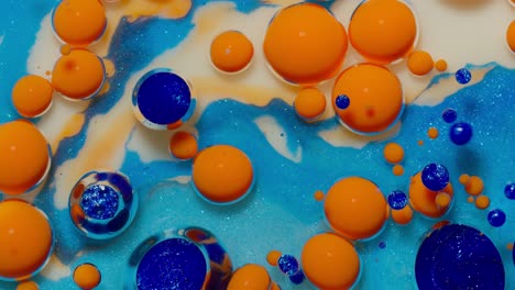 Top-view-movement-of-orange-oil-ink-drops-bubbles,-multicolored-artistic-paint-surface-background