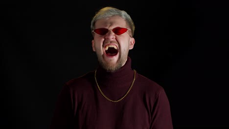 Smiling-stylish-young-man-in-red-sunglasses-looking-at-camera,-laughting-at-loud,-feeling-happiness