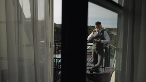 El-Novio,-Un-Hombre-De-Negocios,-Está-Bebiendo-Café-De-Una-Taza-Blanca-En-El-Balcón-De-Su-Casa-En-La-Mañana-De-Su-Boda.