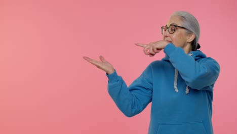 Senior-old-granny-woman-showing-thumbs-up-and-pointing-at-left-on-blank-space,-advertisement-logo