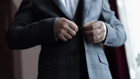 Buttoning-jacket-hands-close-up.-Man-in-suit-fastens-buttons-on-his-jacket-preparing-to-go-out