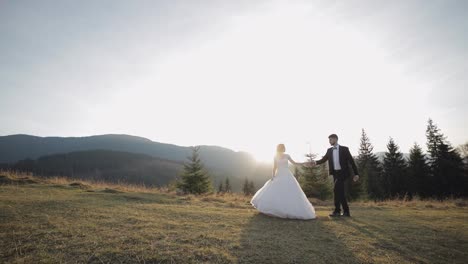 Newlyweds.-Caucasian-groom-with-bride-walking-on-mountain-slope.-Wedding-couple