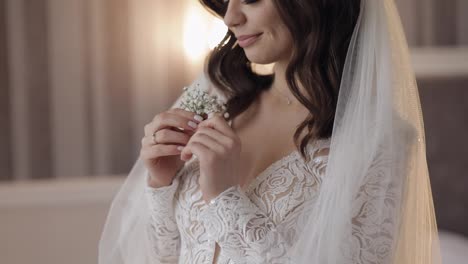 Close-up-of-beautiful-lovely-stylish-smiling-bride-girl-looking-at-gypsophila-flower-bouquet-at-home