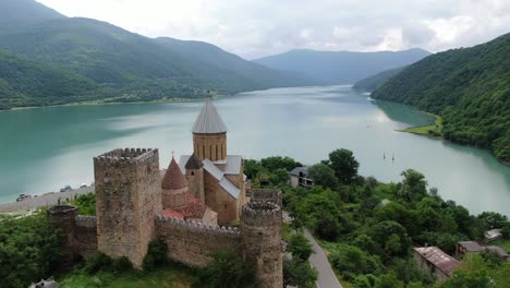 Vista-Aérea-De-Un-Dron-En-Georgia-Que-Vuela-Alrededor-De-La-Fortaleza-Medieval-De-Ladrillos-De-Ananuri-Frente-Al-Lago-Del-Embalse-De-Zhinvali