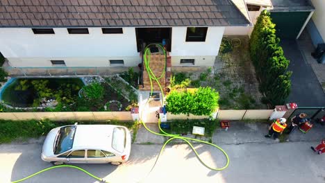 Luftaufnahme---Feuerwehrschläuche-Kommen-Aus-Einem-Haus-Bei-Einem-Brand-In-Oberwaltersdorf,-Österreich