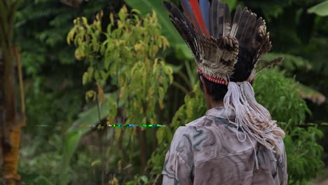 Following-a-tribal-man-wearing-a-feathered-headdress-and-walking-forward