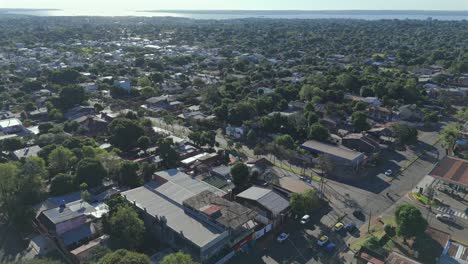 Aerial-footage-capturing-the-urban-landscape-of-posadas-city,-misiones,-argentina,-with-residential-areas,-green-spaces,-and-a-distant-view-of-a-large-body-of-water-of-Parana-river