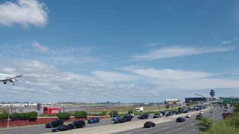 Día-Claro-De-Verano-Con-Avión-Aterrizando-En-La-Pista-Del-Aeropuerto-De-La-Guardia-Con-Tráfico-De-La-Autopista-En-Primer-Plano