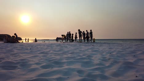 Eine-Silhouette-Von-Menschen-Am-Strand,-Die-Das-Wasser-Genießen-Und-Surfen-Lernen