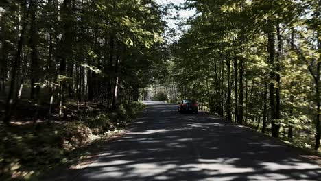 Following-A-Hyundai-Car-Driving-Through-The-Shadows-Of-The-Trees-In-Quebec,-Canada---rolling-shot