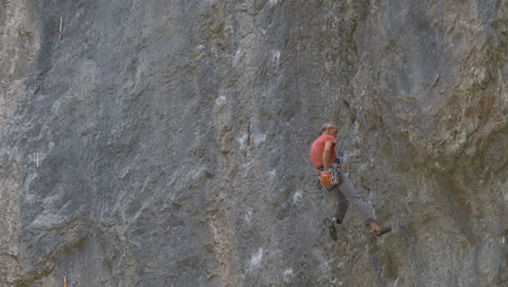 Older-man-climbing-on-very-steep-mountain-cliff,-outdoors-rock-climbing-and-active-lifestyle-concept