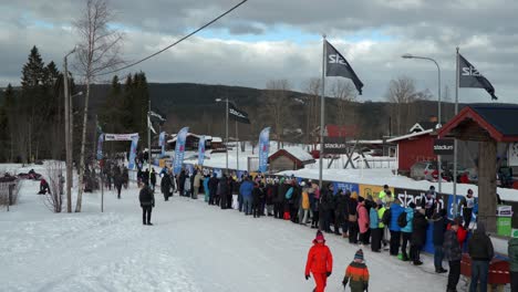 Cross-Country-Skiers-Arriving-at-a-Stop-at-Worlds-Largest-Cross-Country-Ski-Race-Vasaloppet,-Establishing-shot