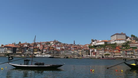 Timelapse-of-River-Duoro-on-stunning-clear-summer-European-day-with-boats-sailing-down-river-and-Ribeira-in-background-with-colorful-houses-and-buildings,-Porto,-Portugal