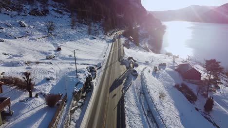 Cars-driving-on-dangerous-road-E16-in-Fossmark-outside-Bergen-during-winter---Sunflares-and-cars-driving-against-camera