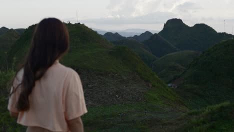 Vista-Con-Teleobjetivo-Medio-De-Una-Mujer-Que-Mira-Hacia-Los-Valles-De-Las-Montañas-Tropicales,-Con-El-Fondo-Enfocado