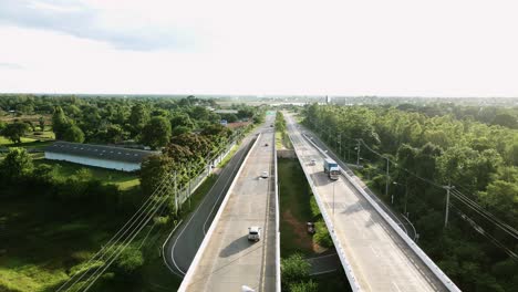 Aerial-wild-view-of-railway-crossing-bridge-and-tree-forest-near-side-with-traffic-on-the-road-in-Khonkaen,-Thailand