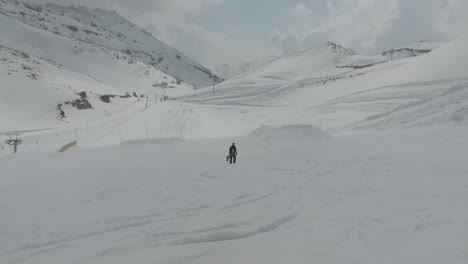 Snowboarder-Sosteniendo-Una-Tabla-De-Snowboard-Y-Caminando-Cuesta-Arriba-Por-Las-Pistas-En-Las-Laderas-Nevadas-Del-Monte-Hermón,-Altos-Del-Golán,-Israel