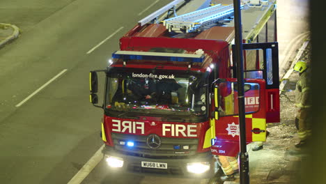 Un-Bombero-Se-Sube-A-Un-Camión-De-Bomberos-En-Londres-Por-La-Noche,-Inglaterra.