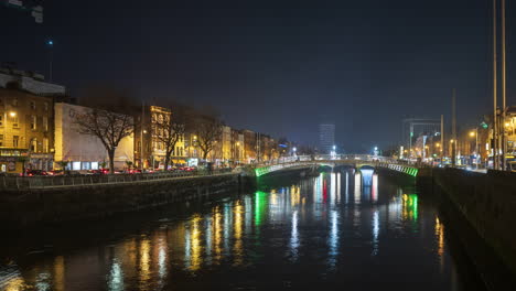 Lapso-De-Tiempo-Del-Tráfico-Nocturno-Y-Personas-Caminando-Por-El-Puente-Que-Se-Refleja-En-El-Río-Liffey-En-El-Centro-De-La-Ciudad-De-Dublín-En-Irlanda