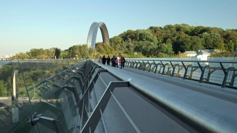 Wide-dramatic-shot-of-people-walk-across-the-glass-bridge-in-Kiev-on-a-warm-autumn-evening