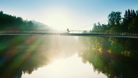 Un-Mochilero-Solitario-Cruza-Un-Puente-En-Una-Mañana-Soleada,-Filmado-Con-Un-Dron