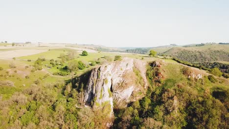 Aerial-drone-shot-towards-Thor's-Cave,-Ashbourne,-Peak-District-at-sunset