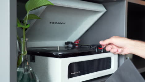 Hombre-Usando-Un-Tocadiscos-Antiguo:-Las-Manos-Sacan-El-Vinilo-De-Su-Funda,-Lo-Colocan-En-El-Tocadiscos-Y-Mueven-La-Cabeza-Hacia-El-Vinilo-Para-Iniciar-La-Música.