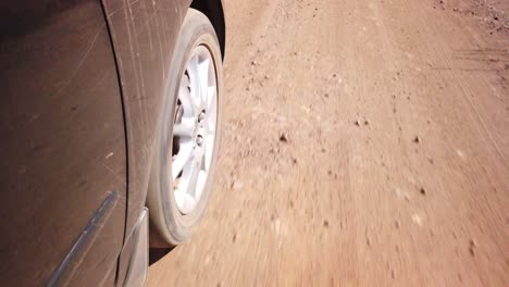 Nahaufnahme-Eines-Autorads,-Das-Auf-Einer-Sand-Schotterstraße-Fährt