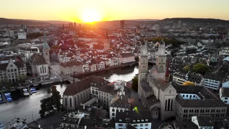 Luftaufnahme-Von-Zürich,-Schweiz-Bei-Sonnenuntergang-Von-Hinter-Der-Grossmünster-Kirche-über-Die-Limmat-Nach-St.