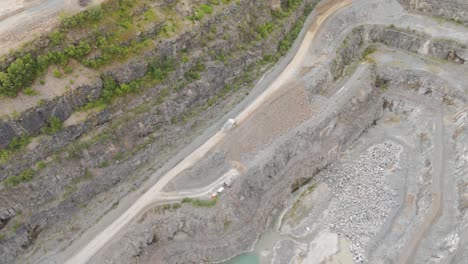 Vista-Aérea-De-Un-Gran-Camión-Industrial-Que-Transporta-Agregados-Recién-Extraídos-Desde-El-Suelo-De-La-Cantera,-Lo-Que-Ilustra-Las-Operaciones-Mineras-En-Curso