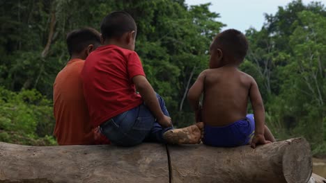 Three-Brazilian-boys-sit-on-a-log-with-their-backs-turned-to-the-camera