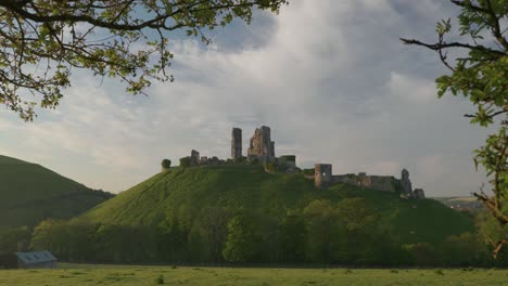 Slow-zoom-in-of-Corfe-Castle-framed-by-green-leaves-in-the-early-morning-light