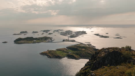 Aerial-view-over-Henningsvær-from-Festvågtind-with-a-man-standing-towards-the-small-islands-in-summer