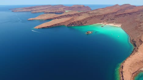 Langsamer-Vorwärtsflug-über-Einzigartige-Klippen-Einer-Einsamen-Insel-Und-Eine-Atemberaubende-Wasserlandschaft-Mit-Einem-Vorbeirasenden-Motorboot-In-Der-Ferne