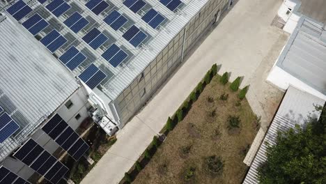 Instalación-Solar-En-Un-Parque-Ecológico,-Toma-Aérea-Inclinada-Hacia-Abajo-Sobre-Oficinas-Modernas