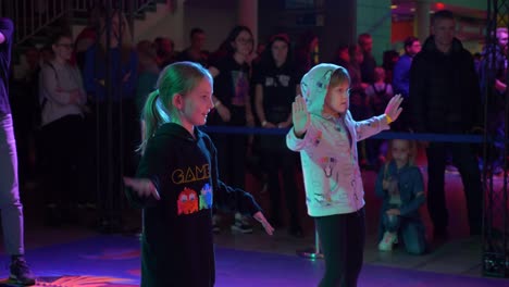 Slow-motion-shot-of-two-little-girls-trying-to-repeat-dancing-moves-from-the-screen