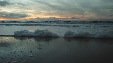 Foam-washed-up-on-the-beach-of-Sylt-with-the-sunset-in-the-background